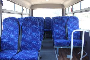 20-Seater bus for hire from Bus Centre Hire, photographed on the inside, showcasing the blue cloth seats and 3-point safety belts.